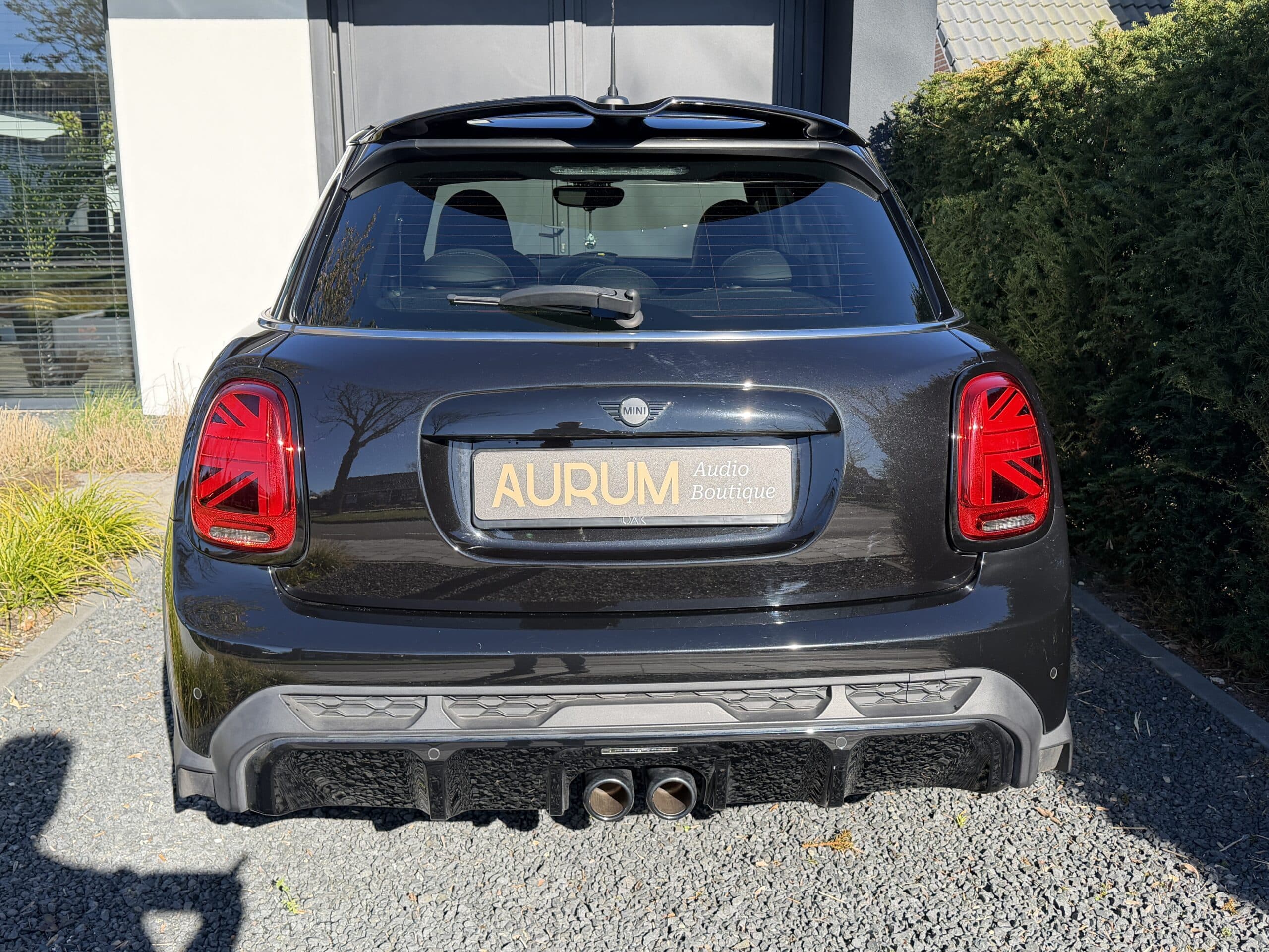 Achterzijde van een zwarte MINI Cooper bij Aurum Boutique, specialist in high-end audiosystemen en exclusieve car audio-oplossingen.